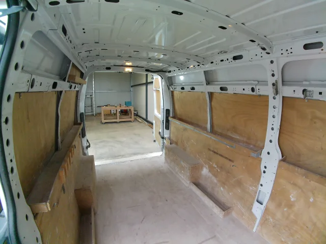 Vue intérieure du fourgon Renault Master Blanc à partir de la porte latéralle avant, stationné sur le parking de Be-O-Be Vans